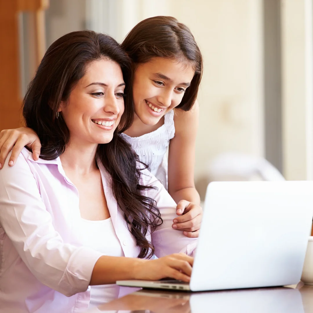 Mother and daughter smiling over a laptop | How Old Do You Have to Be to Invest?
